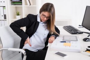 Woman in Home Office Holding Her Low Back in Pain