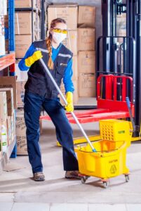 Woman holding onto mop in a warehouse